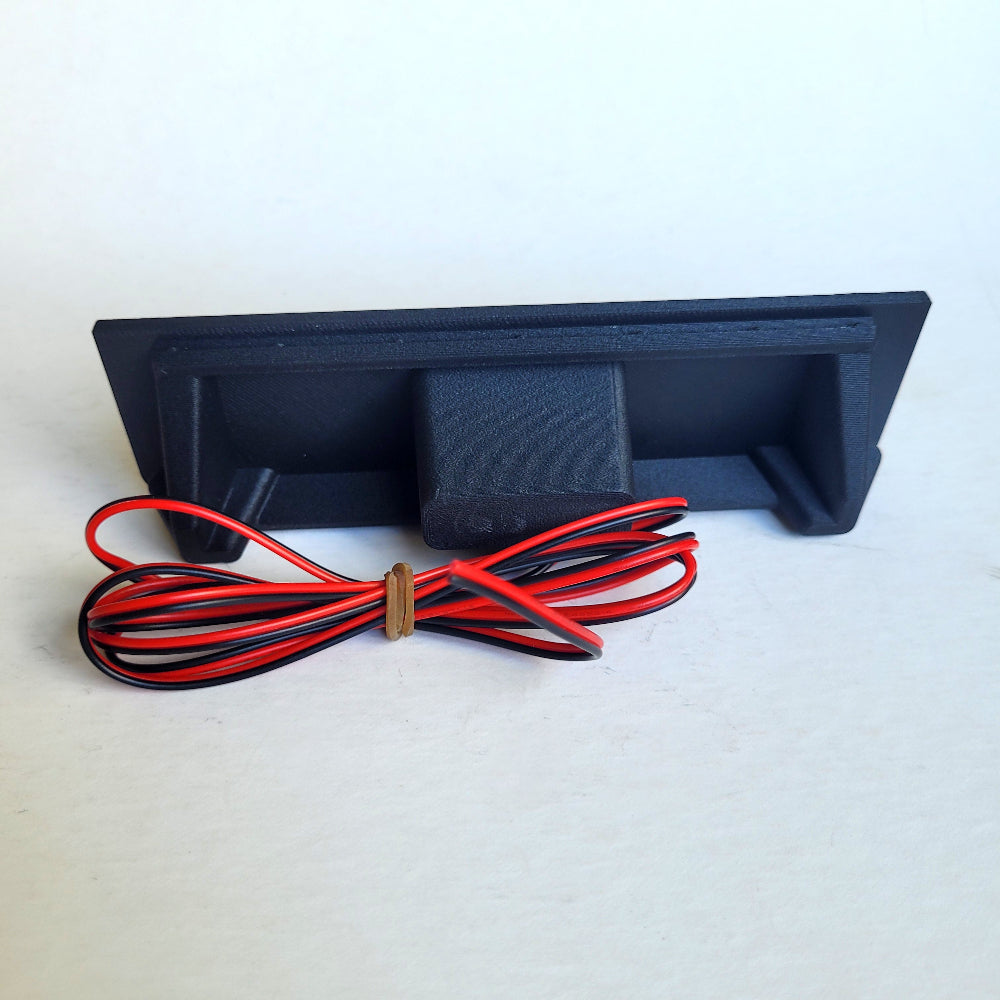 Black rectangular electronic component with red and black wires on a white background